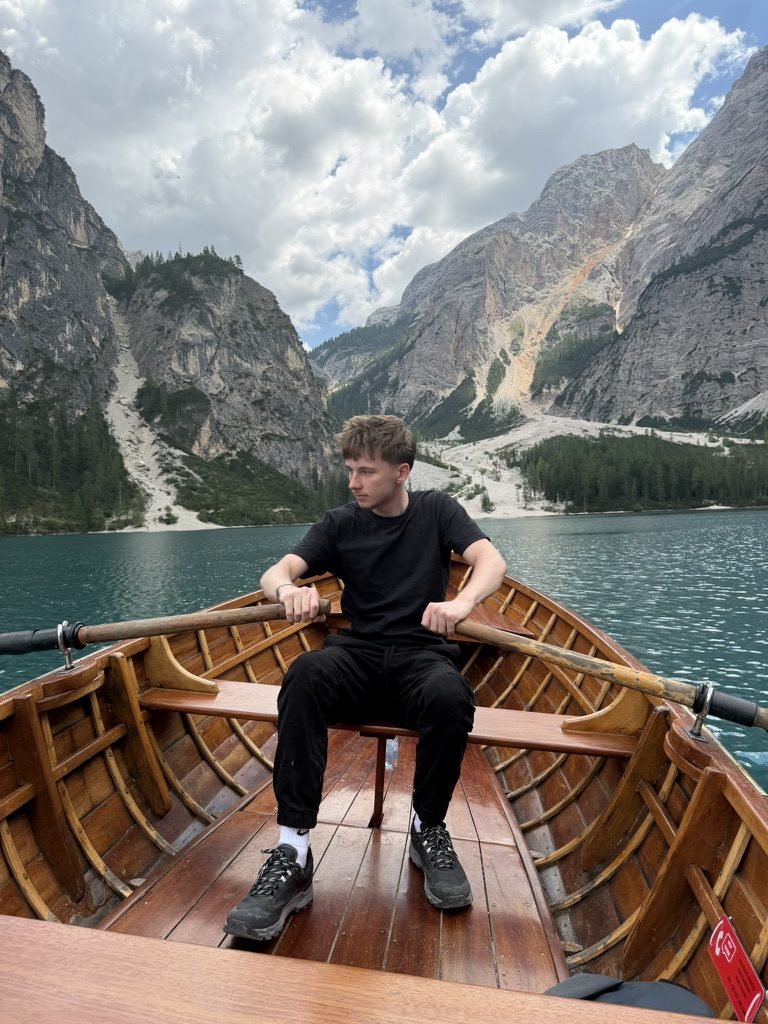 Steven rowing a wooden boat on a mountain lake